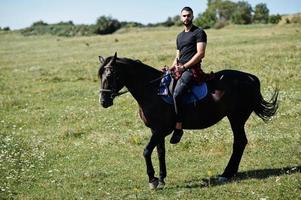 Arab tall beard man wear in black ride arabian horse. photo