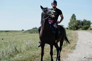 Arab tall beard man wear in black helmet, ride arabian horse. photo