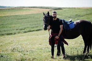 Arab tall beard man wear in black with arabian horse. photo