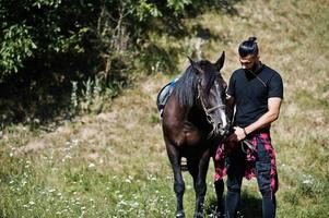 Arab tall beard man wear in black with arabian horse. photo