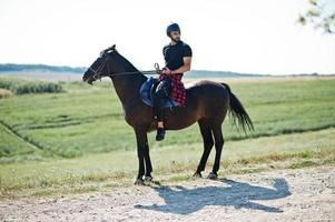 El hombre árabe de barba alta usa casco negro, monta un caballo árabe. foto