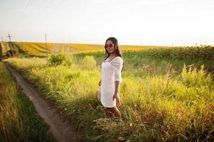 una mujer negra muy joven usa una pose de vestido de verano en un campo de girasoles. foto