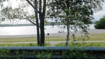 uitzicht uit het zijraam van een snel rijdende auto terwijl u naar een meer en een parkeerplaats kijkt video