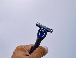 male hand holding a razor black white background concept beard trimming photo