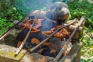 pollo a la parrilla tradicionalmente ahumado con madera y piel de coco, foto cruda de filtro editable