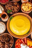 Homemade Romanian Food with polenta, meat, cheese and vegetables. Delicious corn porridge in clay dishes. Mamaliga or polenta, a traditional dish in Moldova, Hungary  and Ukrainian cuisine. photo