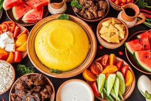 comida rumana casera con polenta, carne, queso y verduras. deliciosas gachas de maíz en platos de barro. mamaliga o polenta, un plato tradicional en moldavia, hungría y cocina ucraniana. foto