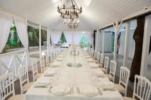 Empty banquet hall ready to receive guests on the summer terrace. white festive table photo