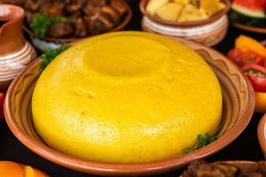 Homemade Romanian Food with polenta, meat, cheese and vegetables. Delicious corn porridge in clay dishes. Mamaliga or polenta, a traditional dish in Moldova, Hungary  and Ukrainian cuisine. photo