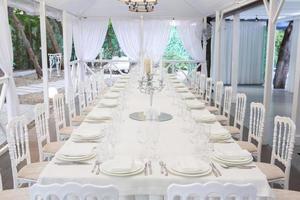 Empty banquet hall ready to receive guests on the summer terrace. white festive table photo