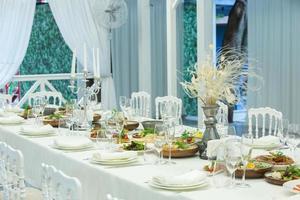 Empty banquet hall ready to receive guests on the summer terrace. white festive table photo