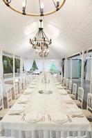 Empty banquet hall ready to receive guests on the summer terrace. white festive table photo