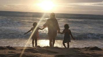 heureuse famille asiatique de mère et de filles s'amusant à jouer sur la plage pendant les vacances d'été au coucher du soleil. voyage d'été en famille à la plage. concept de voyage et de vacances. video