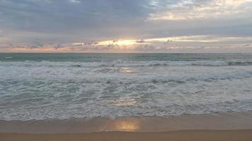 bellissime onde del mare e spiaggia di sabbia bianca nell'isola tropicale. bella vista dei tramonti sul mare. alba sulla spiaggia dell'oceano e nuvole di cielo colorate e drammatiche