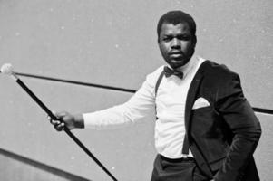 Handsome fashionable african american man in formal wear and bow tie with walking stick. photo