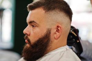 Handsome bearded man at the barbershop, barber at work. photo