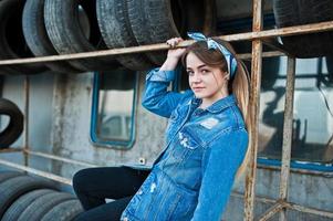 Young hipster girl in jeans jacket and head scarf at tire fitting zone. photo