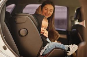 joven madre e hijo en coche. asiento de bebé en silla. concepto de conducción segura. foto