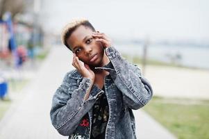 joven afroamericana milenaria en la ciudad. mujer negra feliz con auriculares inalámbricos. concepto de generación z. foto