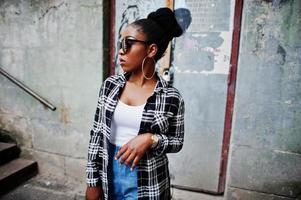 chica afroamericana de hip hop con gafas de sol y pantalones cortos. retrato casual de moda callejera de mujer negra. foto