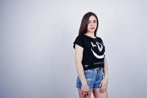 retrato de una chica atractiva en camiseta negra diciendo jajaja y pantalones cortos de mezclilla posando en el estudio. foto