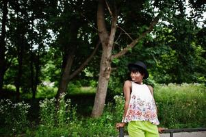 increíble mujer modelo afroamericana en pantalones verdes y sombrero negro posó en el parque. foto