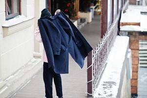 la parte posterior de un elegante hombre afroamericano de estilo urbano usa un abrigo negro en invierno. foto