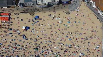 Frente a la playa con vistas al mar en ángulo alto con gente en la ciudad de Bournemouth, Inglaterra, Reino Unido, imágenes aéreas del océano británico video