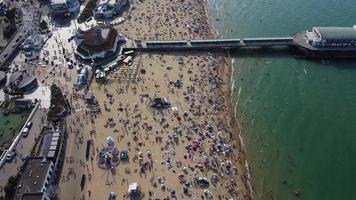 Frente a la playa con vistas al mar en ángulo alto con gente en la ciudad de Bournemouth, Inglaterra, Reino Unido, imágenes aéreas del océano británico