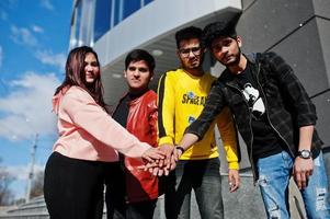 Group of asian people friends stand on stairs outdoor against modern building and hold hands on hands together. photo