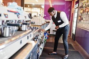 African american bartender at bar holding bootle. Alcoholic beverage preparation. photo