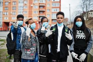 Group of african teenagers friends against empty street with building wearing medical masks protect from infections and diseases coronavirus virus quarantine. photo
