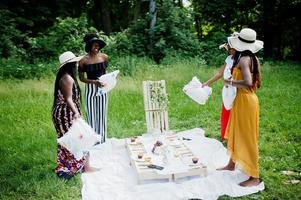 Group of african american girls celebrating birthday party and having fun with pillows outdoor with decor. photo