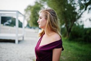 mujer sensual rubia en vestido rojo marsala posando en la playa del resort. foto