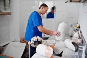 hombre protésico que hace prótesis de pierna mientras trabaja en laboratorio, hace un modelo de yeso. foto