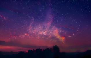 paisaje nocturno con colorida vía láctea y montañas. cielo estrellado con colinas en verano. hermoso universo. fondo del espacio foto