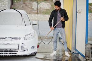 hombre del sur de asia o hombre indio lavando su transporte blanco en el lavado de autos. foto