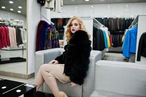 chica rubia de elegancia en abrigo de piel en la tienda de abrigos de piel y chaquetas de cuero. foto