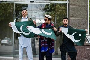 grupo de hombres paquistaníes vestidos con ropa tradicional salwar kameez o kurta con banderas de pakistán. foto