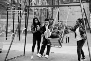 Young millennials african friends on playground, slide and swing. Happy black people having fun together. Generation Z friendship concept.