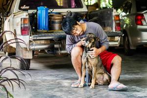 Asian man sits with a dog in his home photo