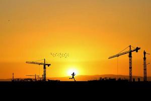 Silhouette of a crane in a construction site. Crane concept for the construction industry photo