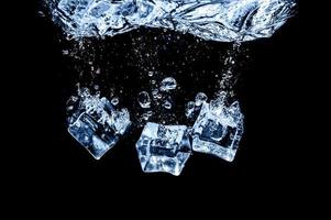 cubos de hielo en agua sobre fondo oscuro de estudio. el concepto de frescura con frialdad de cubitos de hielo. foto