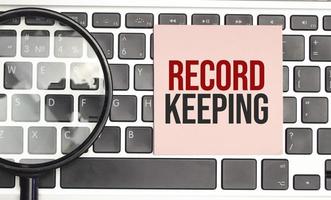 Notepad with the text on laptop RECORD KEEPING photo