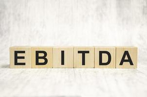 EBITDA text written on wooden block on white background photo