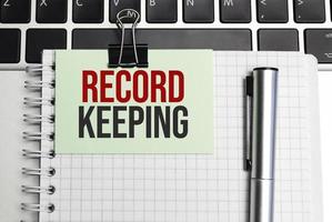 Notepad with the text on laptop RECORD KEEPING photo