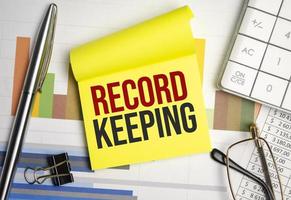 RECORD KEEPING text on the paper with pen photo