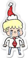 distressed sticker cartoon of a boy crying wearing santa hat vector