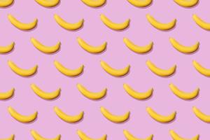 Colorful fruit pattern of fresh yellow bananas on pink background. From top view photo