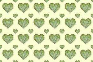 Green leaves in the shape of heart seamless pattern on light yellow background. The concept of love. photo